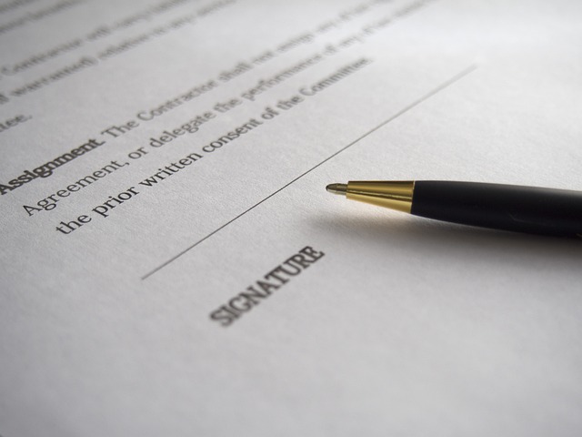 Close-up of a pen resting on a contract near the signature line